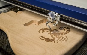 Laser engraving a wood guitar in the laser.